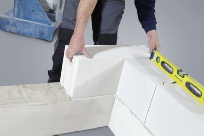 Pose de blocs de parpaing au mortier lors du montage d'un mur